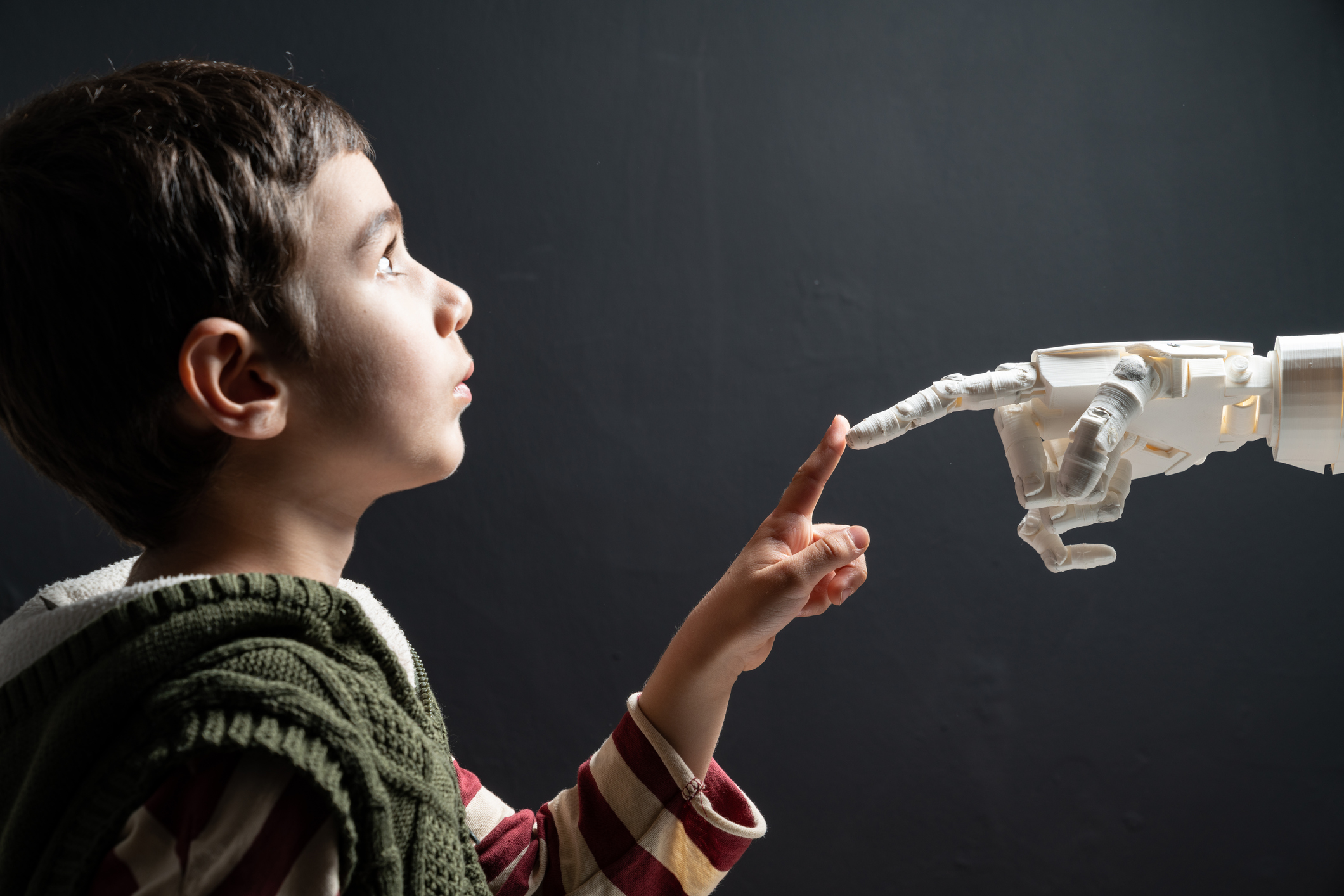 Elementary Schoolboy Touching Robotic Hand